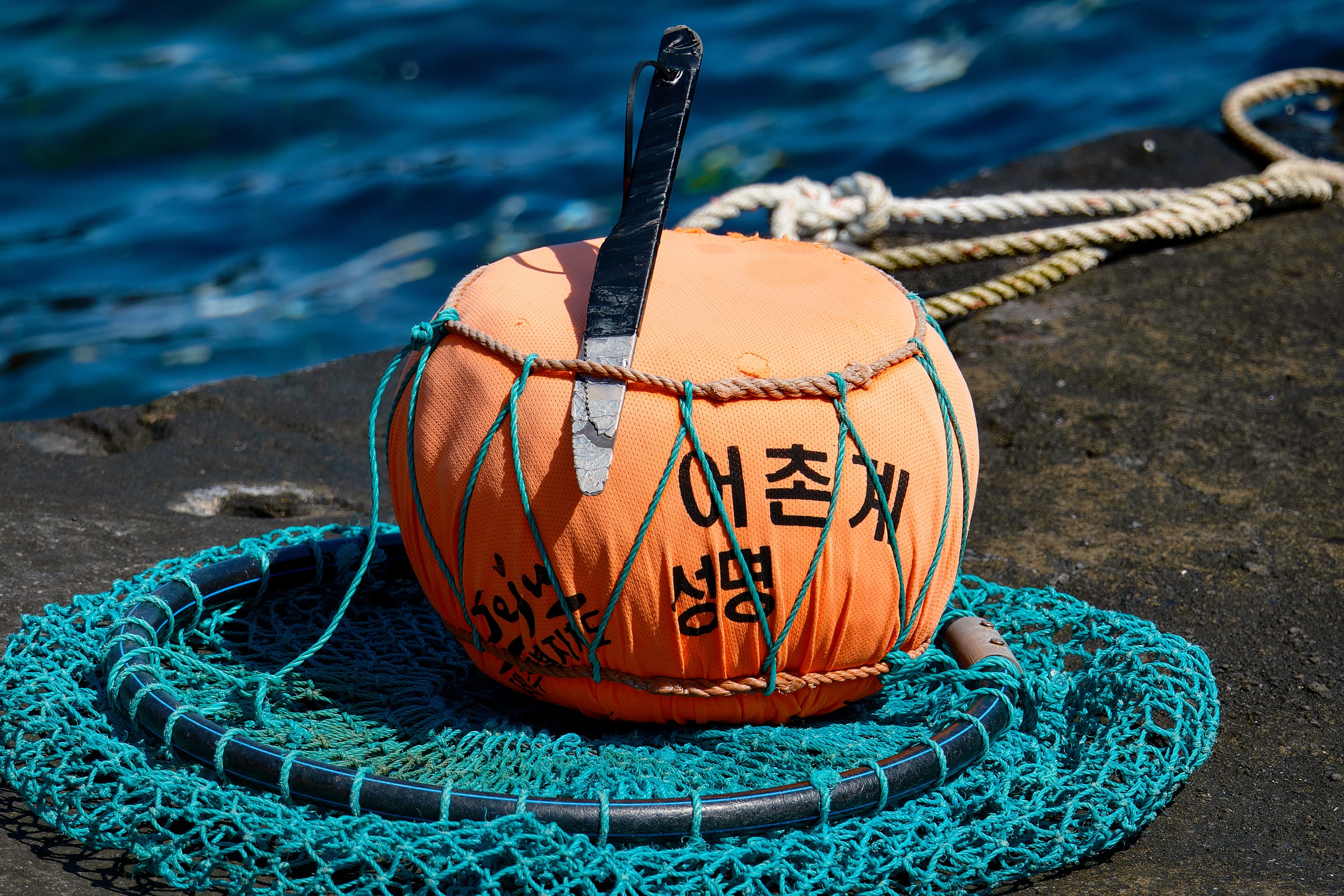 An iconic piece of Jeju's haenyeo (female divers) heritage: a bright orange buoy, accompanied by a net and knife, used by the divers during their underwater expeditions
