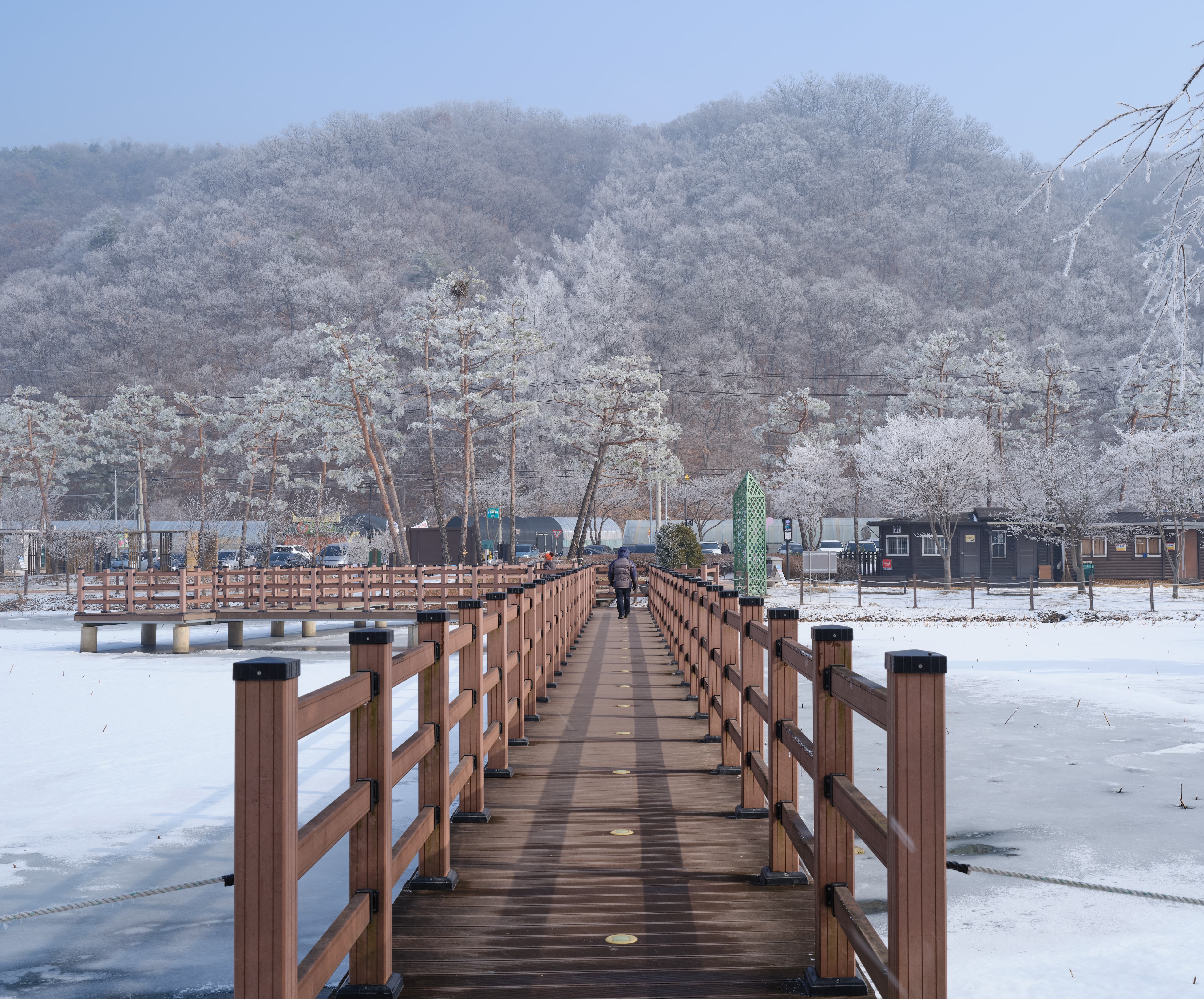 Man walking away on a bridge over a frozen lake