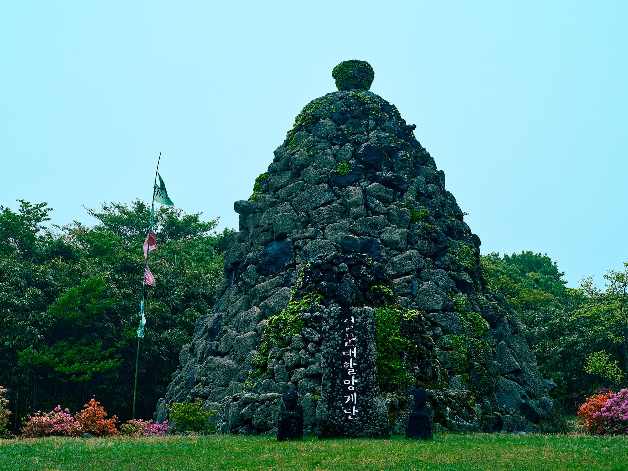 Moss-covered stone cairn with Korean inscription in spring