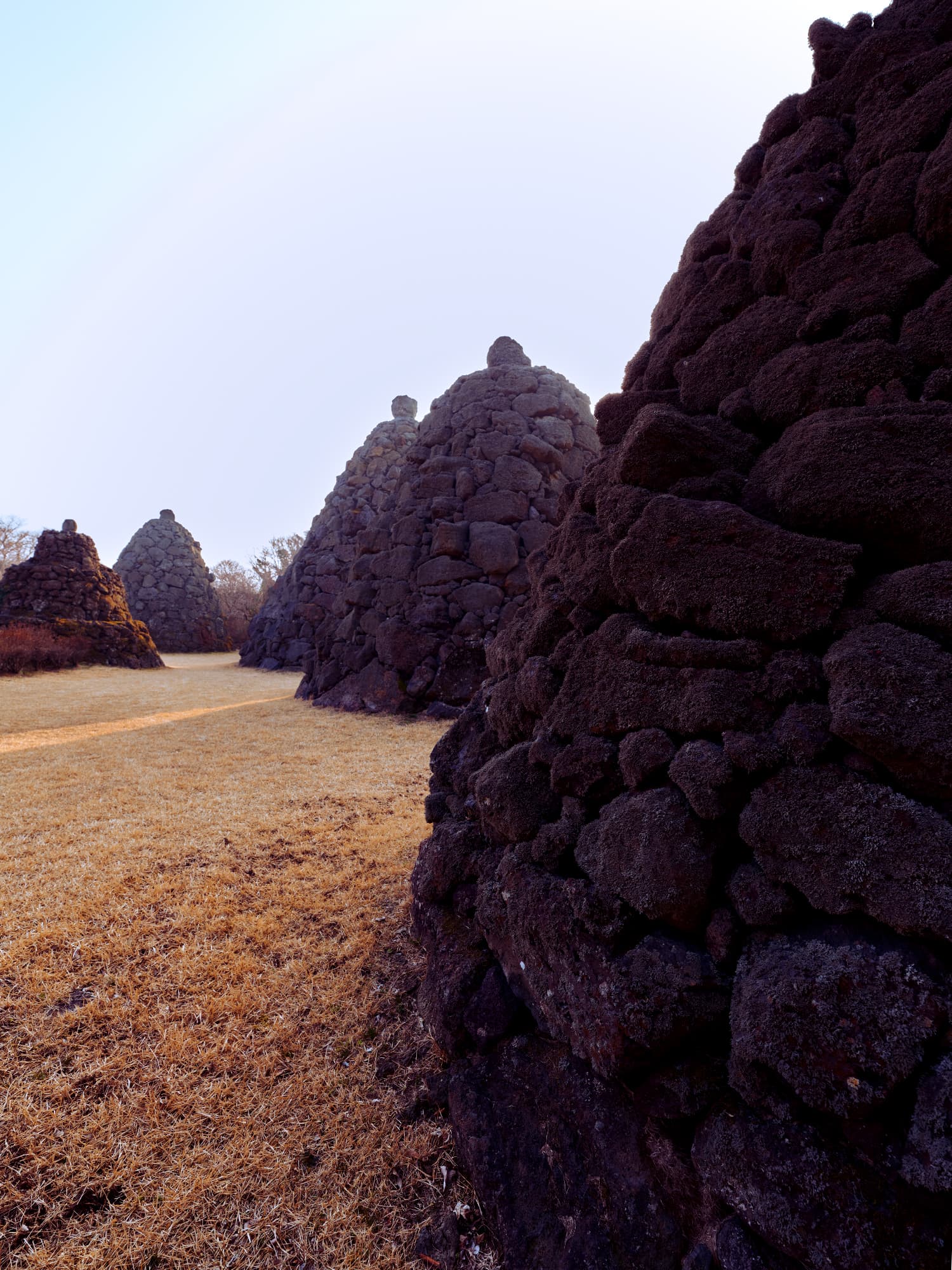 Row of traditional Jeju stone cairn towers at dusk