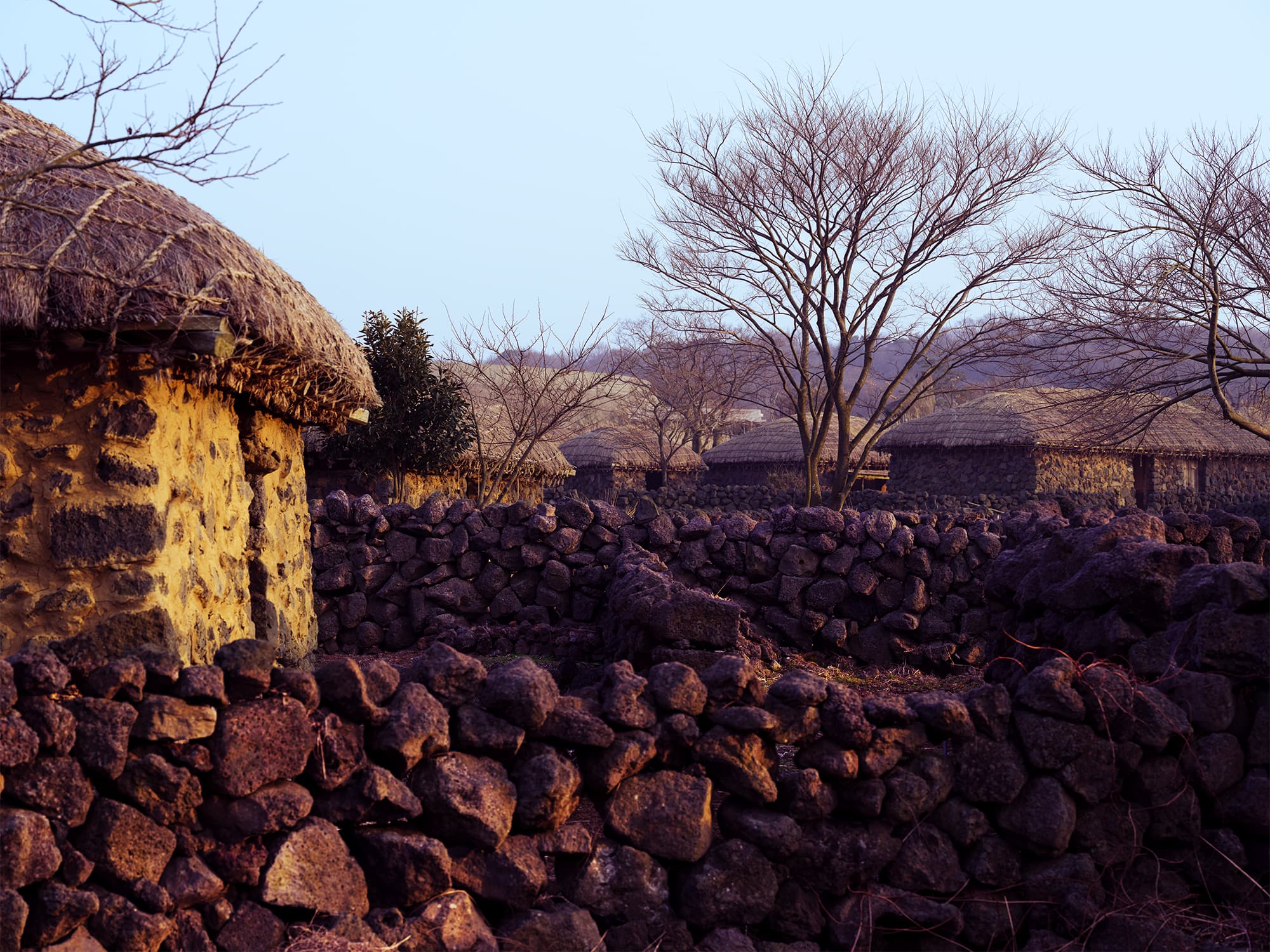 Basalt stone walls with thatched village rooftops behind