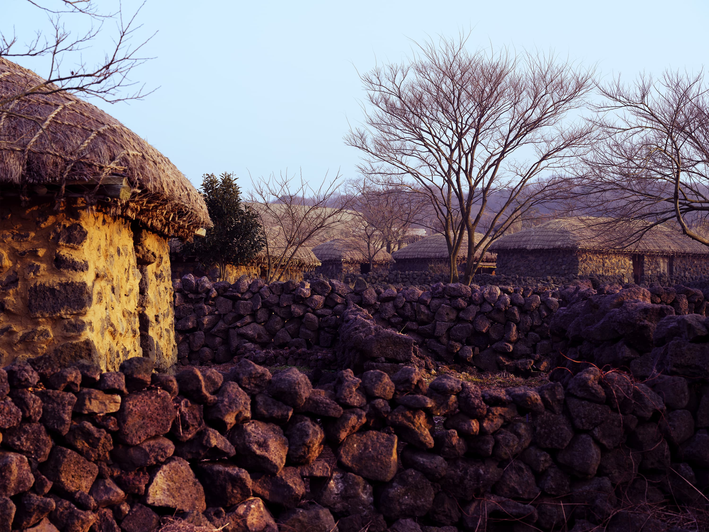 Basalt stone walls with thatched village rooftops behind