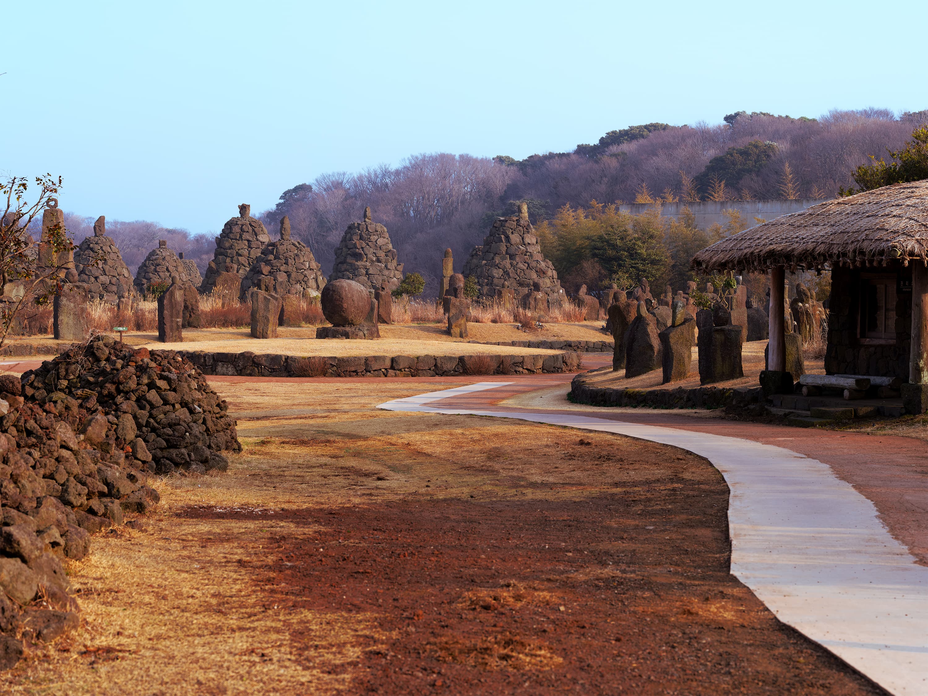 Winding path through stone cairns and a thatched hut